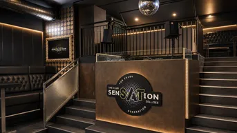 Moderner Clubbereich mit DJ-Pult, Ledersitzbänken und einer Discokugel, ideal für Veranstaltungen.