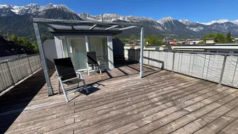 Große Dachterrasse mit Holzboden und atemberaubendem Bergblick, ideal zum Entspannen im Freien.