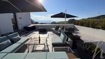 Großzügige Sonnenterrasse mit bequemen Loungemöbeln, Sonnenschirmen und weitem Blick auf die Berge und das Tal.