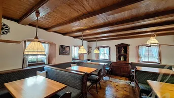 Traditioneller Essbereich mit Holzbalkendecke, rustikalen Möbeln und gefliestem Boden, der eine gemütliche Atmosphäre schafft.