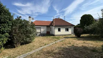 Rückansicht des Hauses mit großem Gartenbereich unter blauem Himmel.
