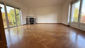 Helles Wohnzimmer mit Fischgrätparkett, Kamin und Zugang zu einem französischen Balkon.