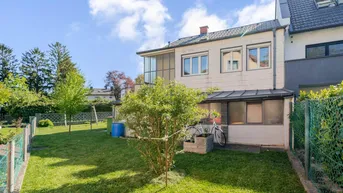 Gepflegter Gartenbereich mit Rasenfläche, Sträuchern und Blick auf die Rückseite des Hauses.