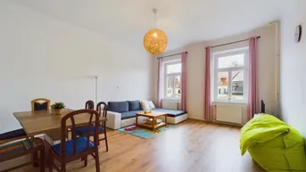 Heller Wohn- und Essbereich mit Laminatboden, gemütlichem Sofa und Esstisch.
