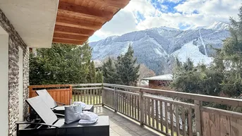 Geräumiger Balkon mit bequemen Liegestühlen und atemberaubendem Blick auf die verschneiten Berge.
