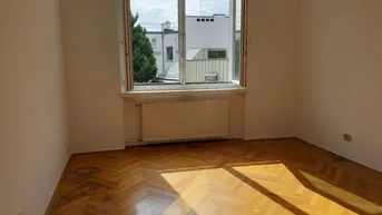 Helles Schlafzimmer mit Fischgrätparkettboden und Blick auf die umliegenden Dächer.