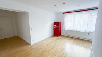 Helles Wohnzimmer mit Parkettboden, Einbaustrahlern und einem auffälligen roten Kühlschrank.