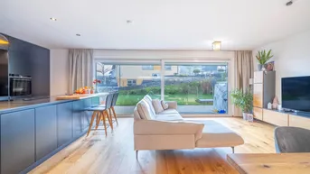 Helles, offenes Wohnzimmer mit Holzboden, beigem Sofa und Blick in den Garten.
