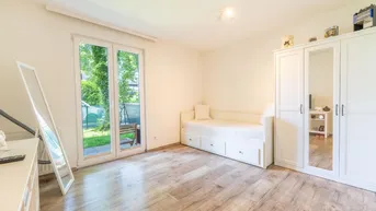 Helles Zimmer mit Holzboden, Tagesbett, weißem Kleiderschrank und direktem Zugang zum Garten.