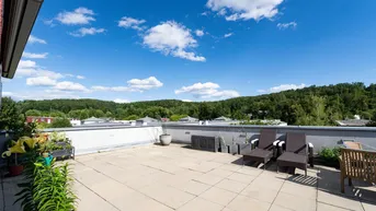 Große Dachterrasse mit bequemen Lounge-Möbeln und weitem Blick ins Grüne unter blauem Himmel.