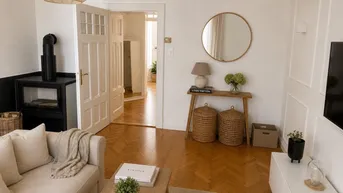 Gemütliches Wohnzimmer mit Sofa, Holzboden und einem modernen Holzofen.