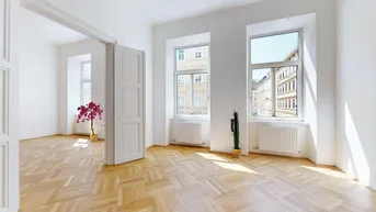 Helles Zimmer mit Fischgrätparkettboden, hohen Fenstern und Blick auf die Stadt.