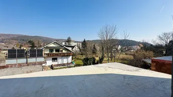 Panoramablick auf eine ländliche Umgebung mit Häusern, Bäumen und Hügeln unter klarem Himmel.