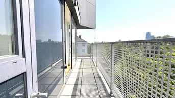 Langer, sonniger Balkon mit Metallgeländer und Blick auf die Stadt und Bäume.