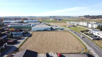 Luftaufnahme eines großen unbebauten Grundstücks umgeben von Wohn- und Gewerbegebäuden mit Fernblick.
