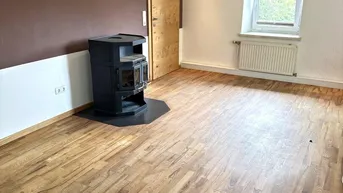 Gemütlicher Raum mit Holzboden, Kaminofen und Holzdecke, ideal als Wohn- oder Schlafzimmer.