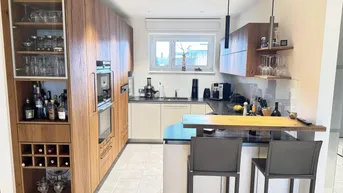 Moderne Küche mit Holzelementen, integrierten Geräten und einer Frühstücksbar für geselliges Kochen.