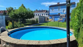 Runder Aufstellpool im Garten mit Außendusche und Blick auf das blaue Haus.