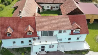 Luftaufnahme eines ländlichen Anwesens mit mehreren Gebäuden und roten Ziegeldächern.