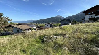 Blick auf Wohnhäuser und Berge in einer ländlichen Umgebung mit hohem Gras.