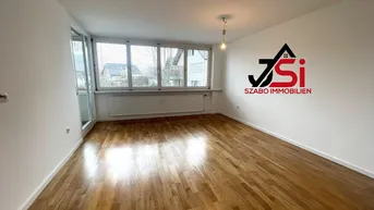 Helles Zimmer mit Parkettboden und Zugang zu einem verglasten Balkon, ideal als Wohnbereich.