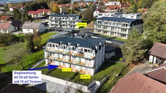 Luftaufnahme einer Wohnanlage mit mehreren Gebäuden, Gärten und Terrassen in grüner Umgebung.