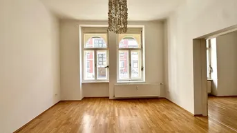 Helles, leeres Zimmer mit Parkettboden und zwei hohen Bogenfenstern, bereit zur individuellen Gestaltung.