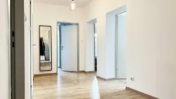 Heller Flur mit modernem Holzfußboden, weißen Wänden und mehreren Türen, der einen gepflegten Zustand zeigt.