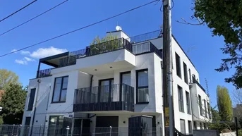 Moderne weiße Wohnhausfassade mit schwarzen Balkongeländern und großen Fenstern.