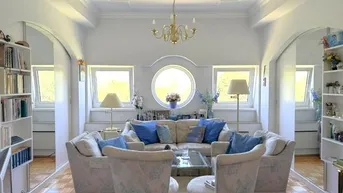 Helles Wohnzimmer mit bequemen Sitzmöbeln, Parkettboden und interessanten Fensterformen.