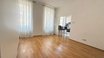 Heller Wohnbereich mit Holzparkettboden und offener Verbindung zur Küche, ideal für modernes Wohnen.