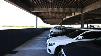 Überdachter Parkplatz mit modernen Fahrzeugen und weitem Blick in die Ferne.