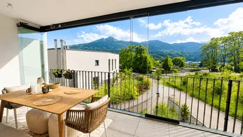 Helles, verglastes Balkon mit Esstisch und Stühlen, bietet einen weiten Bergblick.