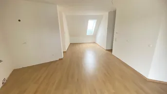 Helles Zimmer im Dachgeschoss mit Schrägdecken und neuem Laminatboden, ideal für Wohn- oder Schlafbereich.