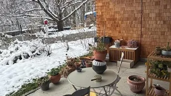 Überdachte Terrasse mit Sitzgelegenheiten und Blick auf eine verschneite Winterlandschaft.