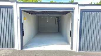 Leere, neuwertige Garagenbox mit Betonboden und weiß gestrichenen Wänden, bereit zur Nutzung.