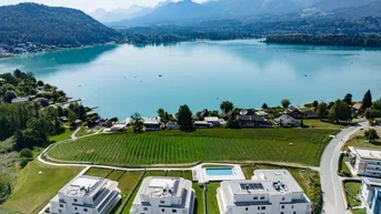Luftaufnahme einer modernen Wohnanlage mit Blick auf den See, Berge und umliegende Weinberge.
