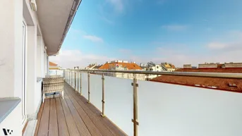 Langer Balkon mit Holzboden und Glasgeländer, bietet einen weiten Blick über die Dächer der Stadt.