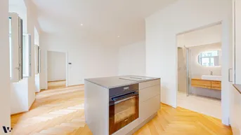 Moderne Kücheninsel mit integriertem Backofen und Induktionskochfeld, angrenzend an ein stilvolles Badezimmer.