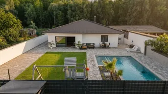 Vogelperspektive eines modernen Einfamilienhauses mit großem Garten, Pool und Kinderspielplatz.
