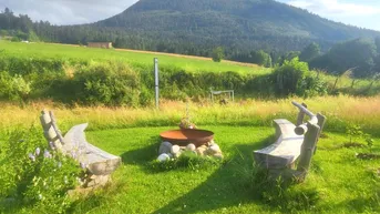 Rustikale Sitzgelegenheiten aus Holz mit Feuerstelle und weitem Blick auf die Berge.