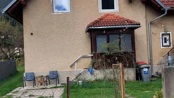 Einfaches Einfamilienhaus mit Satteldach und kleinem Vorgarten in ländlicher Umgebung.