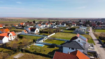 Weitläufige Luftaufnahme einer Wohnsiedlung mit Einfamilienhäusern und viel Grünfläche.