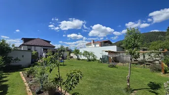 Großer, gepflegter Garten mit Rasenfläche und Blick auf die umliegenden Häuser und Berge.