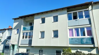 Mehrfamilienhaus mit Balkonen und gepflegter Fassade unter blauem Himmel.