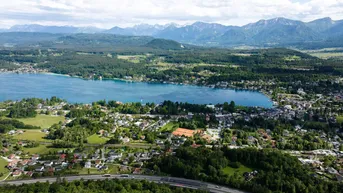 Panoramablick aus der Vogelperspektive auf einen See, eine Stadt und die umliegende Berglandschaft.