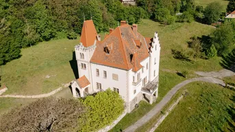 Luftaufnahme des historischen Anwesens mit weitläufigen Grünflächen und Wegen.
