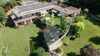 Luftaufnahme eines weitläufigen Anwesens mit großem Garten, Wohnhaus und Solaranlage auf dem Dach.