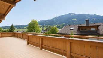 Geräumige Holzterrasse mit Bergblick und viel Platz für eine gemütliche Sitzecke.