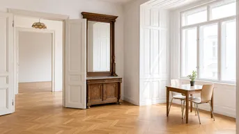Heller Wohnraum mit Fischgrätparkett, großen Fenstern und antiken Möbeln, der in weitere Zimmer führt.